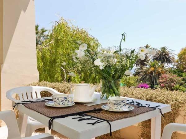 un tavolo con piatti e tazze e un vaso di fiori di Hotel Residence Villa Igea Capri a Capri