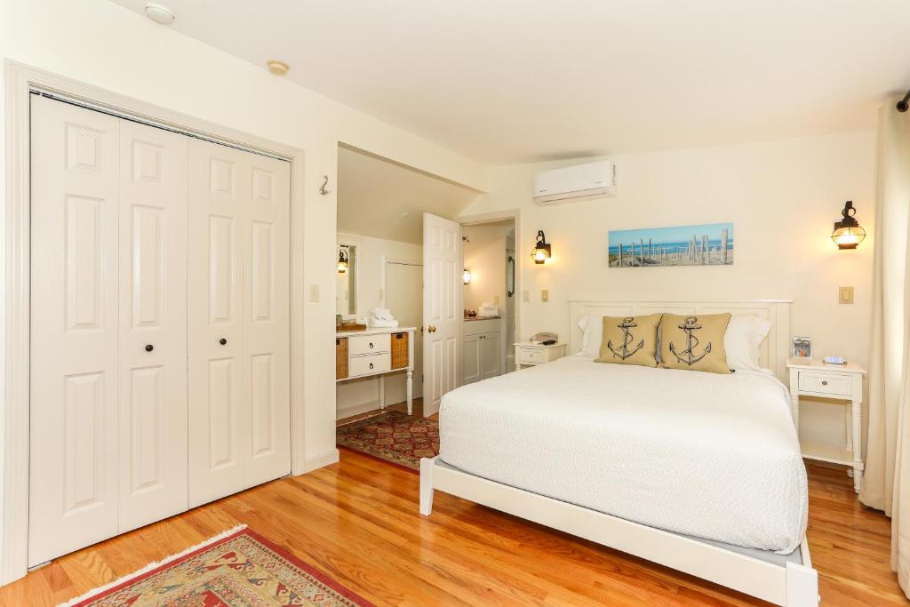 a white bedroom with a bed and a bathroom at Eagle Wing Inn - Cape Cod in Eastham