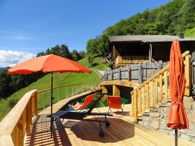 a wooden deck with an umbrella and a chair at Brentwaldhof Appartements in Cornedo all'Isarco