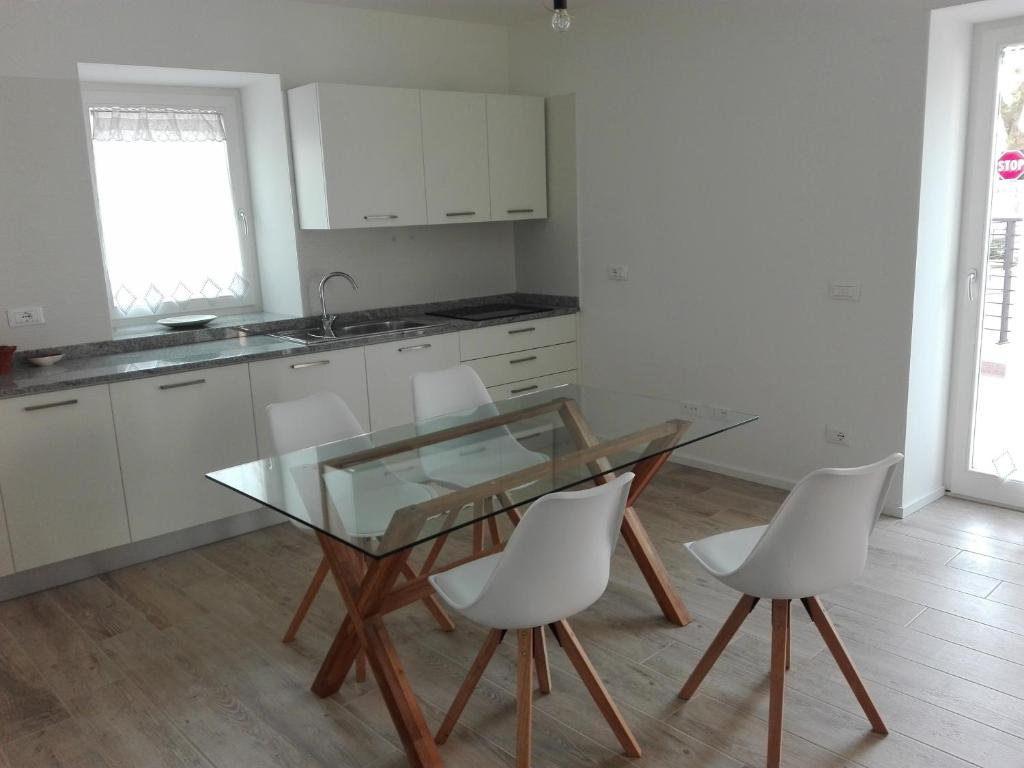 eine Küche mit einem Glastisch und weißen Stühlen in der Unterkunft Residenza Pedrotti in Levico Terme