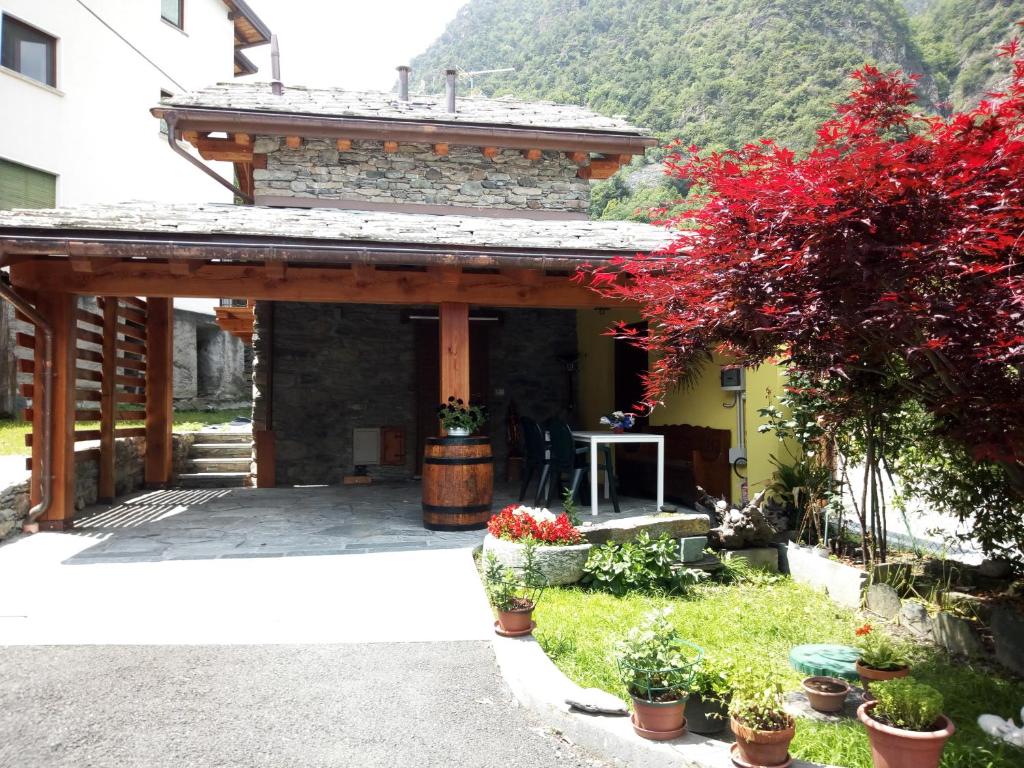 a stone building with a porch with flowers and plants at Acero Rosso in Champdepraz