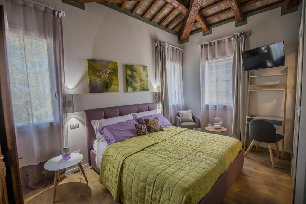 um quarto com uma cama, uma televisão e janelas em A casa di V-Ale em Treviso