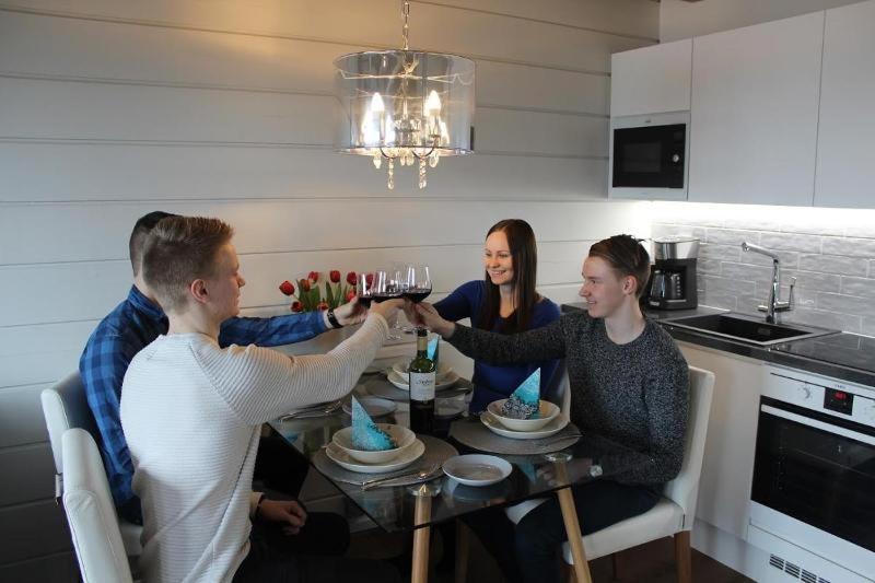 um grupo de pessoas sentadas em torno de uma mesa com copos de vinho em Naava Chalet 304 Pandatupa em Ahtari