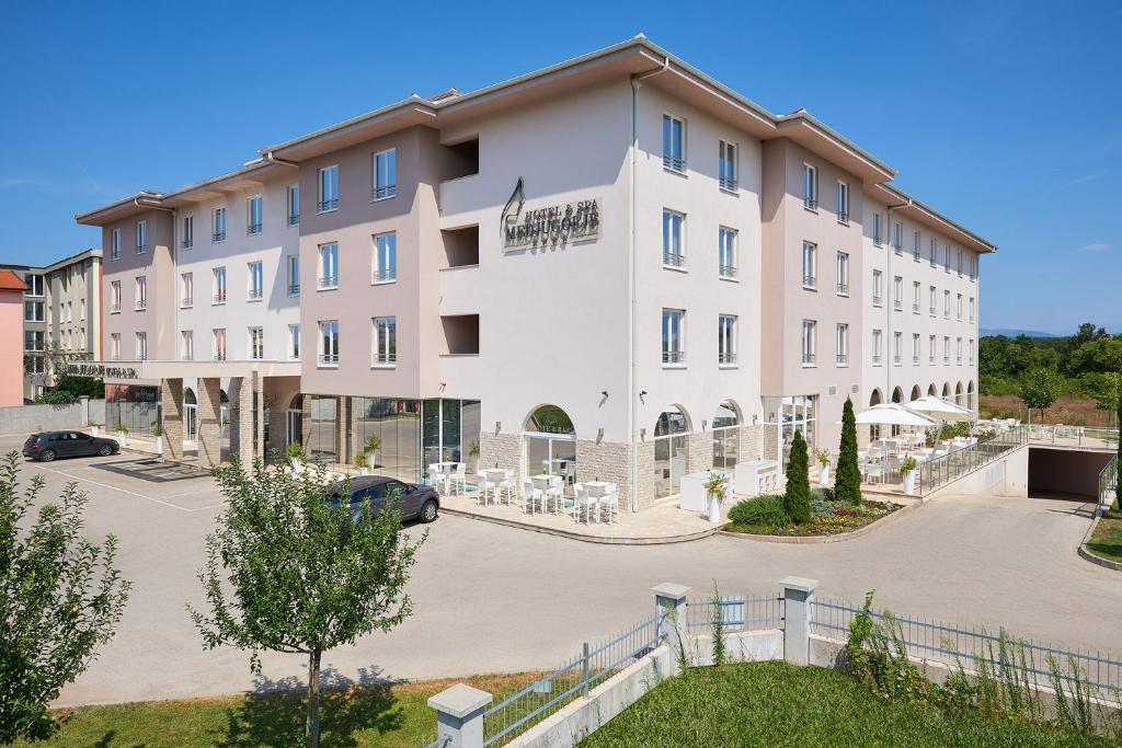 a large white building with a parking lot at Medjugorje Hotel & Spa in Međugorje