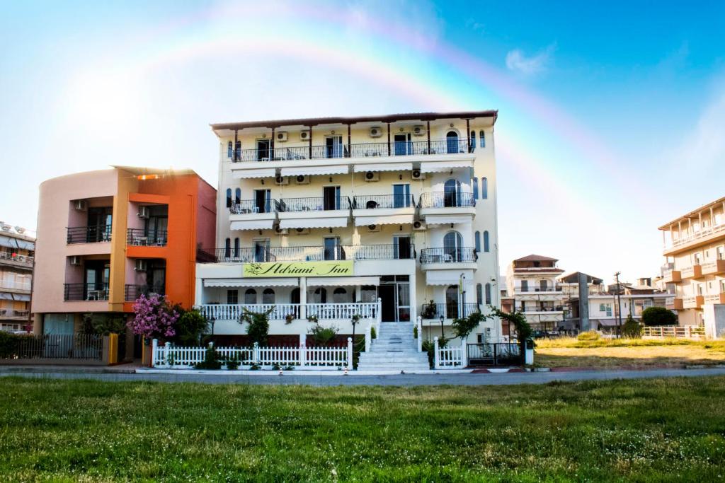 a white building with a white fence in front of it at Adriani Inn in Paralia Katerinis