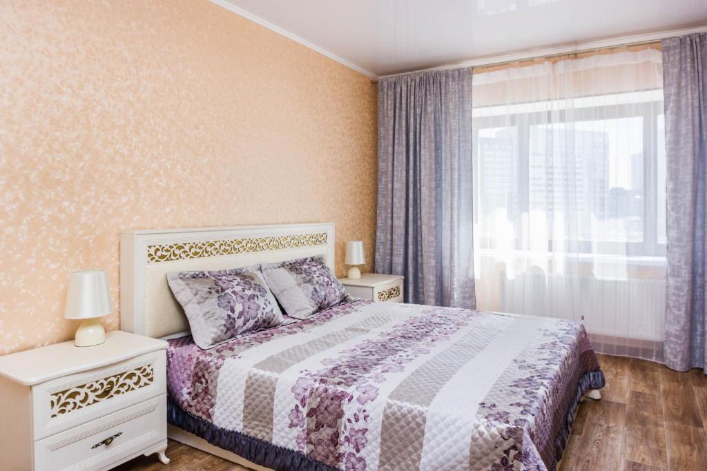 um quarto com uma cama e uma janela em Apartment on Kharkovskaya 66 em Tiumen