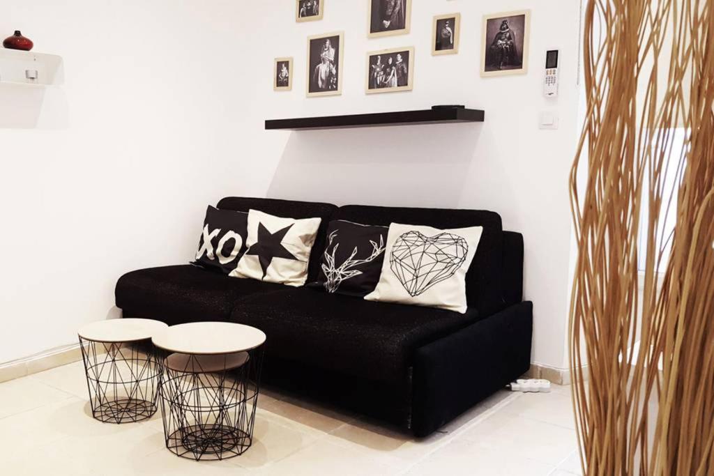 ein schwarzes Sofa im Wohnzimmer mit zwei Tischen in der Unterkunft GregBnb-com - Studio Cosy - CLIMATISÉ - WIFI - 15min Gare in Toulon