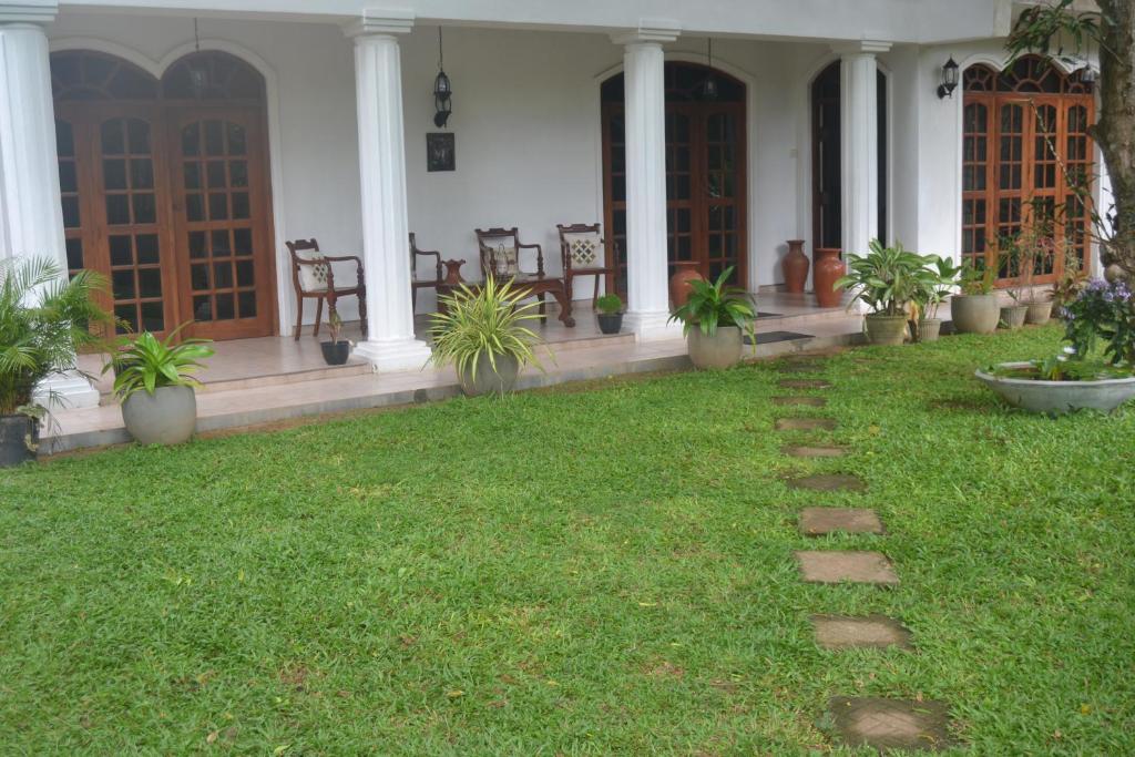 a porch of a house with chairs and grass at Kuma Beach side Villa in Wadduwa