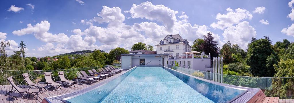 a swimming pool with chairs and a house at Hotel Villa Hügel in Trier