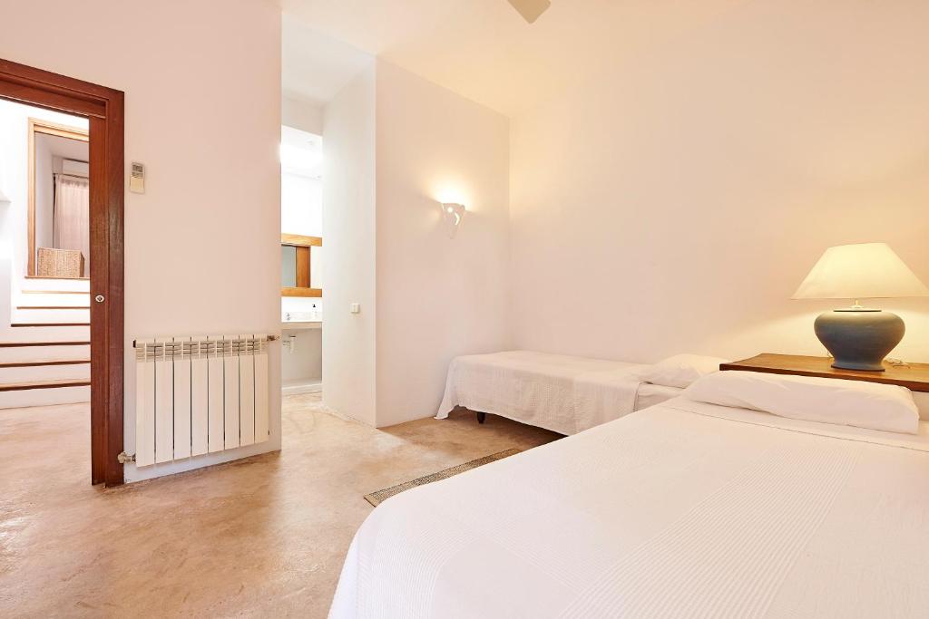 a white room with two beds and a lamp at Can Mares in Cala Tarida