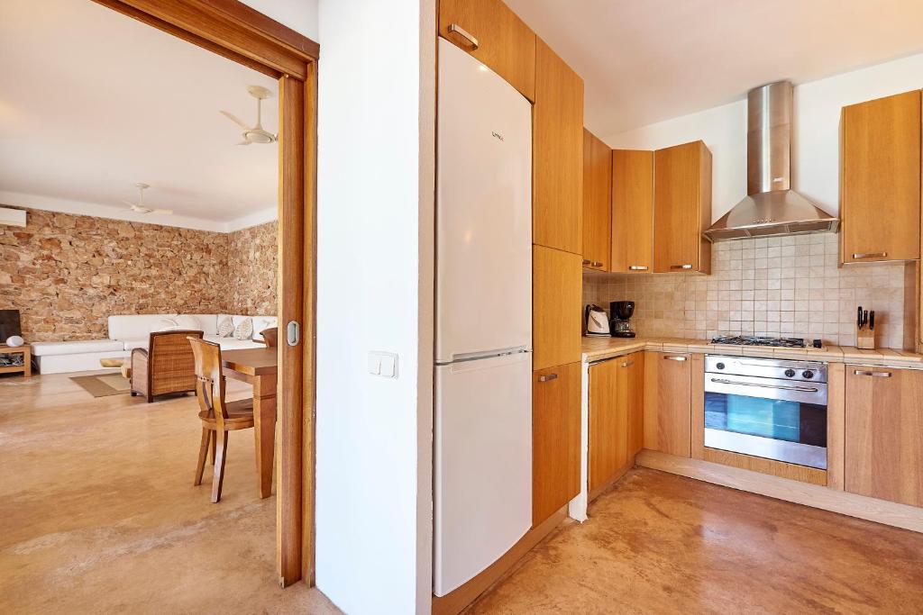 a kitchen with wooden cabinets and a table in a room at Can Mares in Cala Tarida