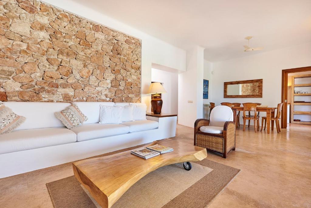 a living room with a white couch and a stone wall at Can Mares in Cala Tarida