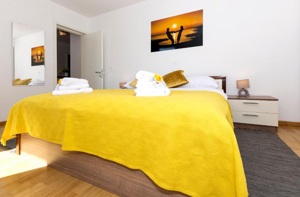 a bedroom with a yellow bed with towels on it at Cvit Jadrana in Split