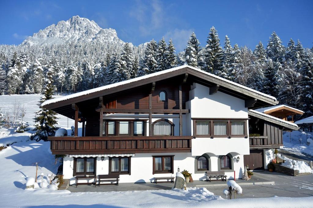 una casa nella neve con una montagna sullo sfondo di Appartement Jöchl a Ellmau