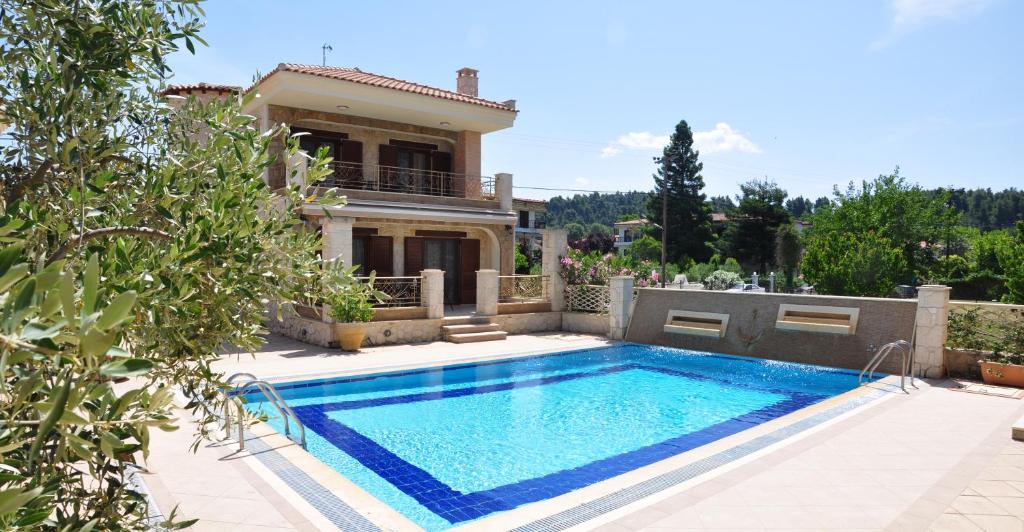 a villa with a swimming pool in front of a house at Anastasia Villas in Siviri