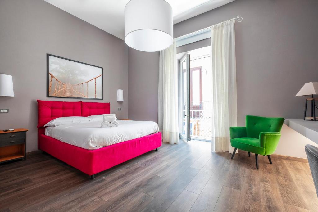 una camera con letto rosso e sedia verde di Maison Borghese a Sorrento