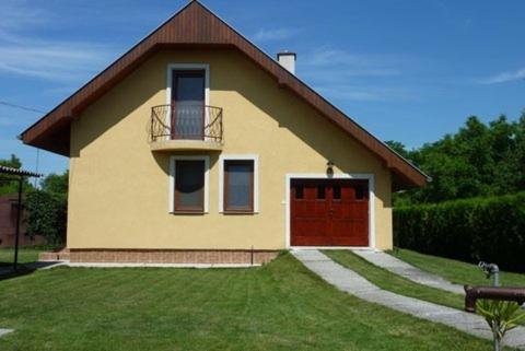 una pequeña casa amarilla con puerta roja en Apartman Foldes Tibor, en Veľký Meder