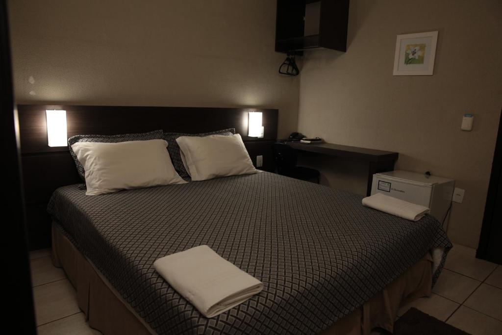 1 dormitorio con 1 cama con 2 almohadas blancas en Samba Três Lagoas, en Três Lagoas