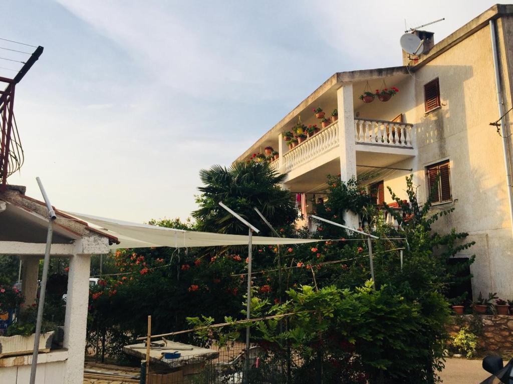 a large white building with a balcony with plants at Apartman Nena in Čepljani