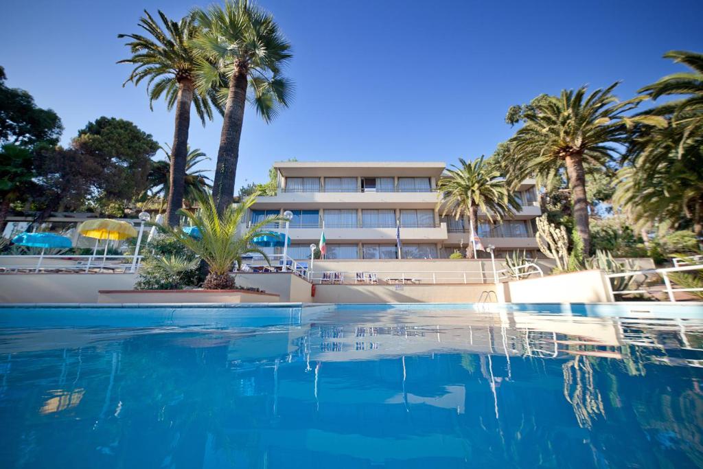 una piscina con palmeras y un edificio en Nyala Suite Hotel, en San Remo