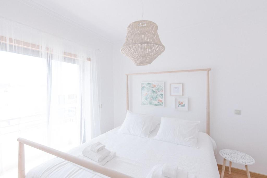 Dormitorio blanco con cama y lámpara colgante en Casas de Mar - Barco, en Olhão