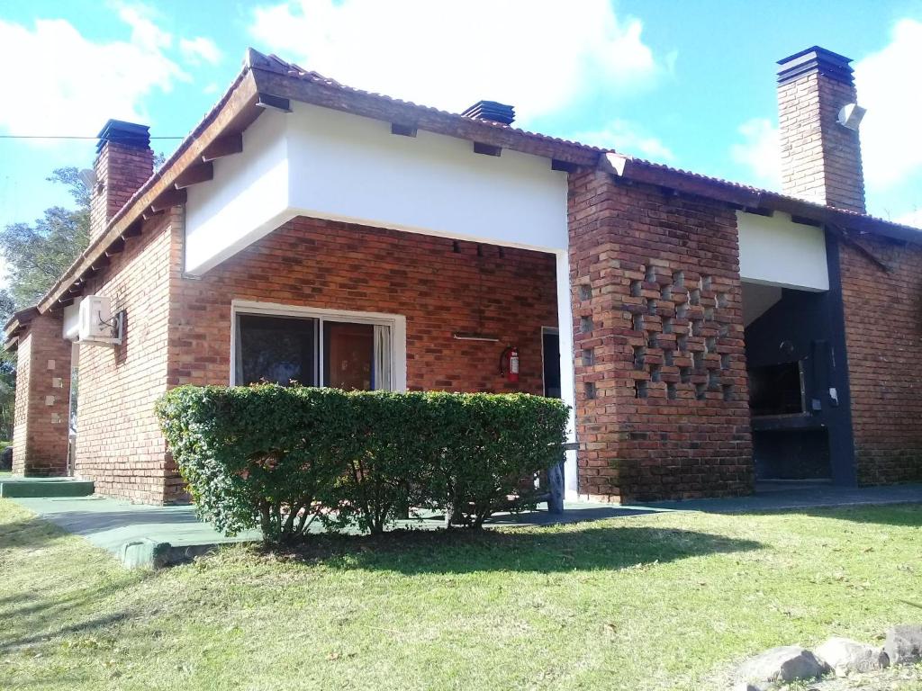 a brick house with a bush in front of it at Brisas Del Rio Apart Hotel in Termas del Daymán