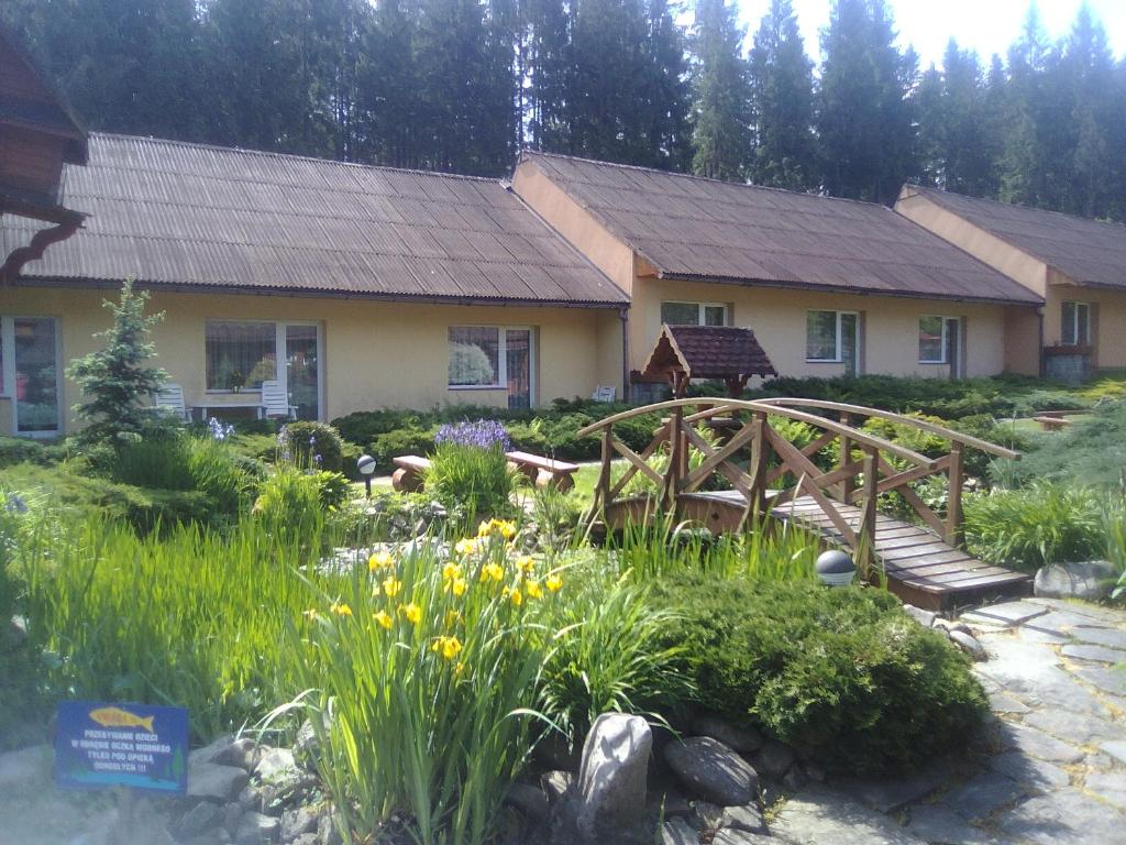 uma casa com uma ponte de madeira em frente a um jardim em Ośrodek Wczasowy "GRONOSTAJ" em Rajcza