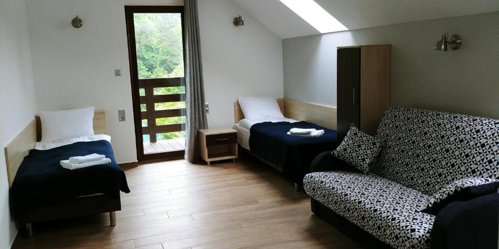 Zimmer mit 2 Betten, einem Sofa und einem Fenster in der Unterkunft Przy Dolinie in Paczółtowice