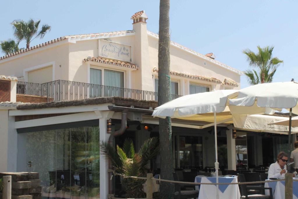 a restaurant with tables and umbrellas in front of a building at The Residence by the Beach House Marbella in Marbella