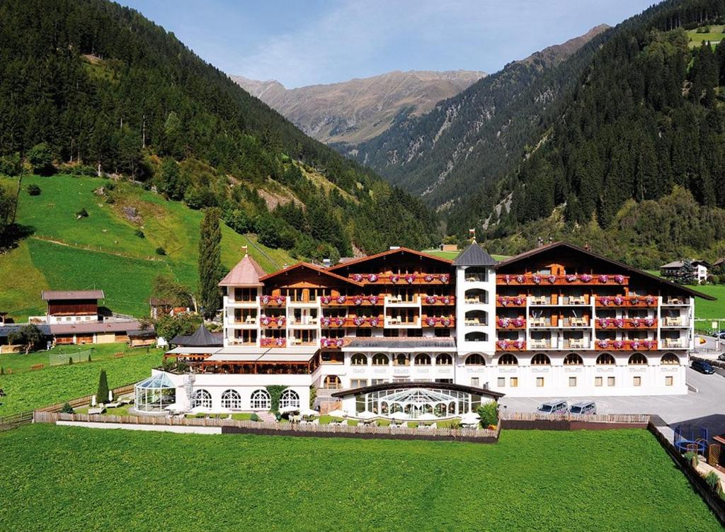 un grande edificio in un campo con montagne sullo sfondo di Wellness & Relax Hotel Milderer Hof a Neustift im Stubaital