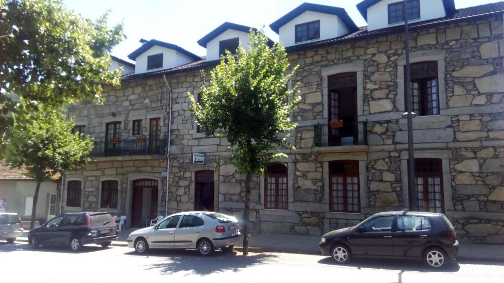 two cars parked in front of a stone building at Pensao Avenida in Caldelas