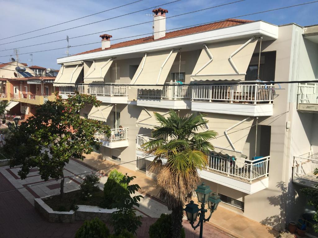 um grande edifício branco com varandas e palmeiras em Phaethon Apartments & Studios em Kallithea Halkidikis