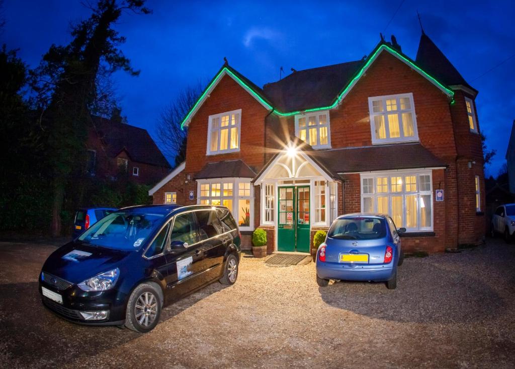 two cars parked in front of a house at night at Gatwick Turret Guest House in Horley