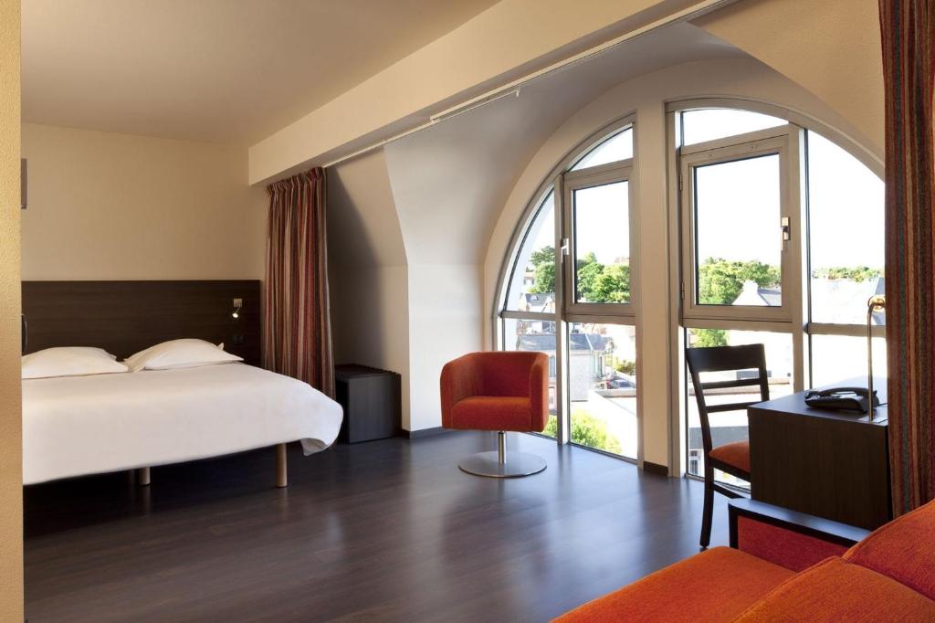 ein Hotelzimmer mit einem Bett und einem großen Fenster in der Unterkunft Escale Oceania Pornichet La Baule in Pornichet