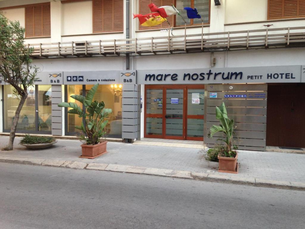 a store on the side of a building with plants in front at Mare Nostrum Petit Hôtel in Pozzallo