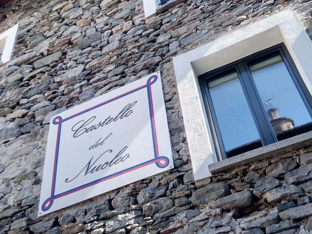 ein Schild an der Seite eines Steingebäudes mit Fenster in der Unterkunft Guesthouse "Castello del Nucleo" in Intragna