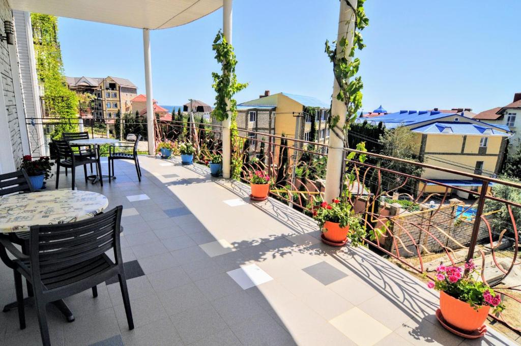 un balcón con mesas, sillas y plantas en Near Camel’s Humps Hotel, en Koktebel