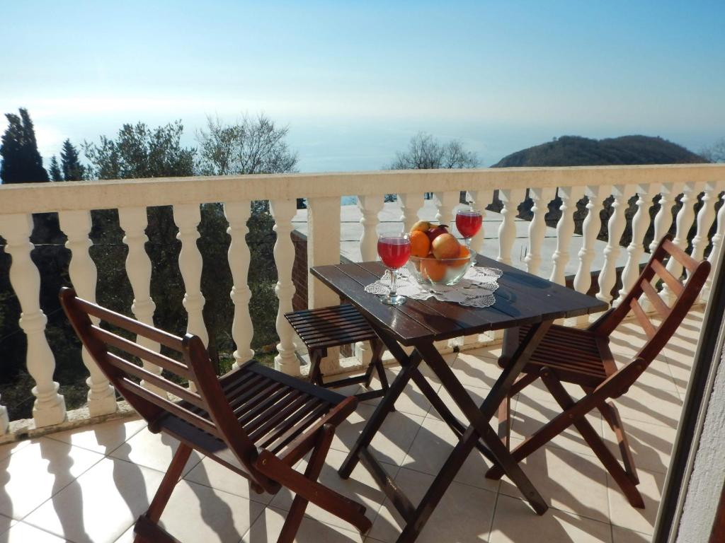 een tafel met twee glazen wijn en fruit op een balkon bij House Stijepovic in Petrovac na Moru