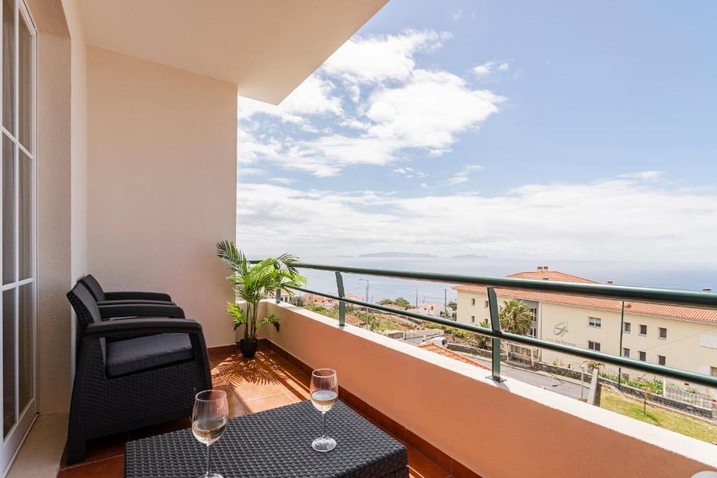 - un balcon avec deux chaises et une table avec des verres à vin dans l'établissement Caniço V by An Island Apart, à Caniço