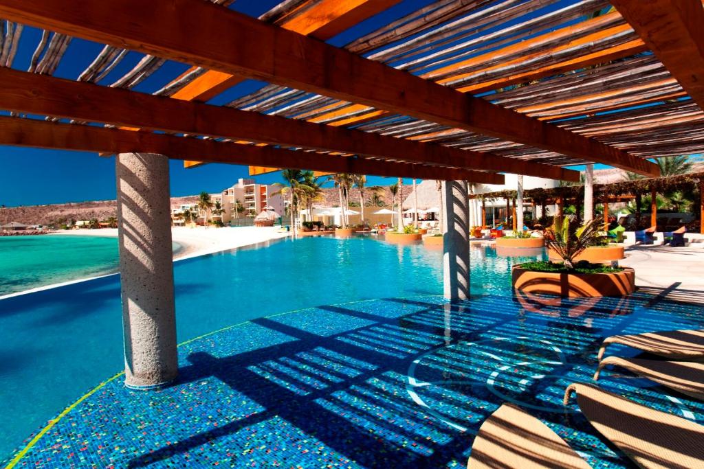 a swimming pool with lounge chairs and a roof at LC 1A- Beach Club & Housekeeping included - Golf Cart in La Paz