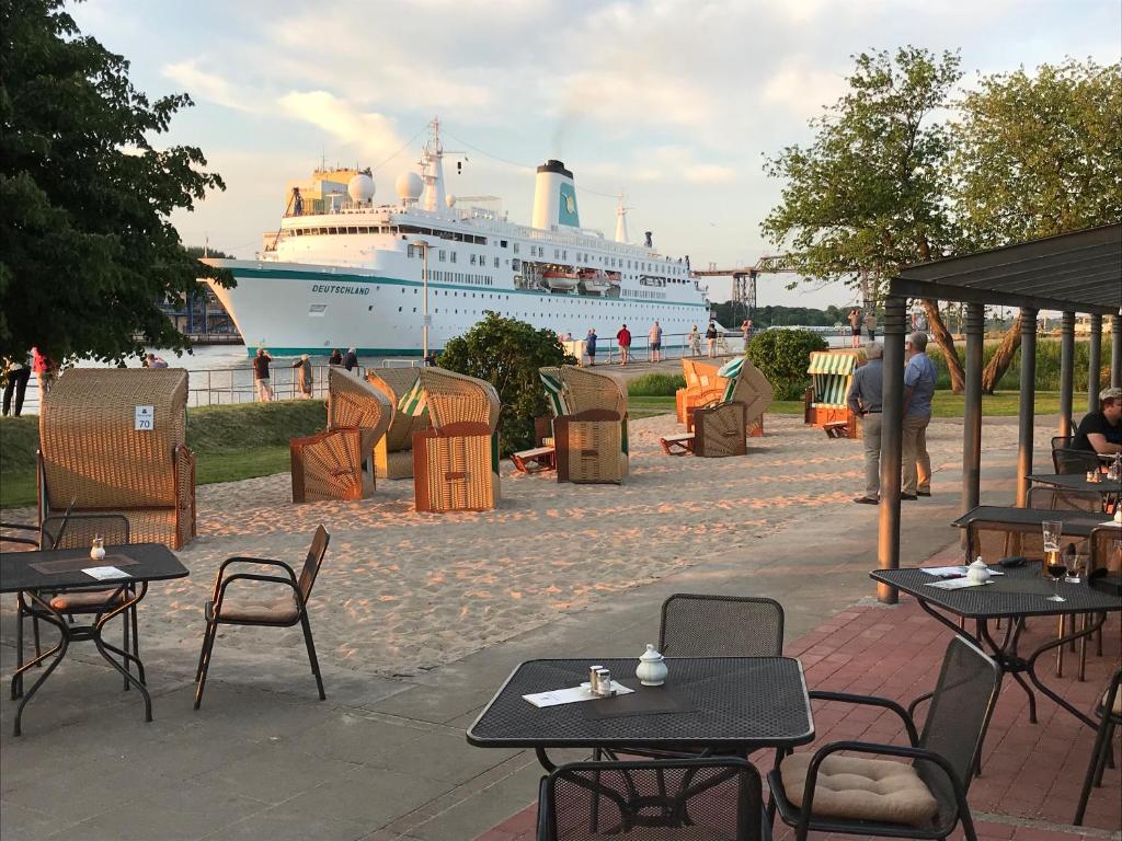 un navire de croisière dans l'eau avec des tables et des chaises dans l'établissement Kanal-Haus "Das Gästehaus direkt am NOK", à Osterrönfeld