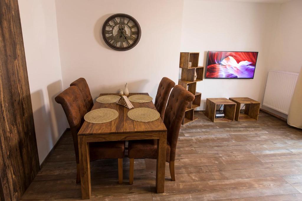 a dining room table with chairs and a clock on the wall at Rooftop apartment I. in Košice