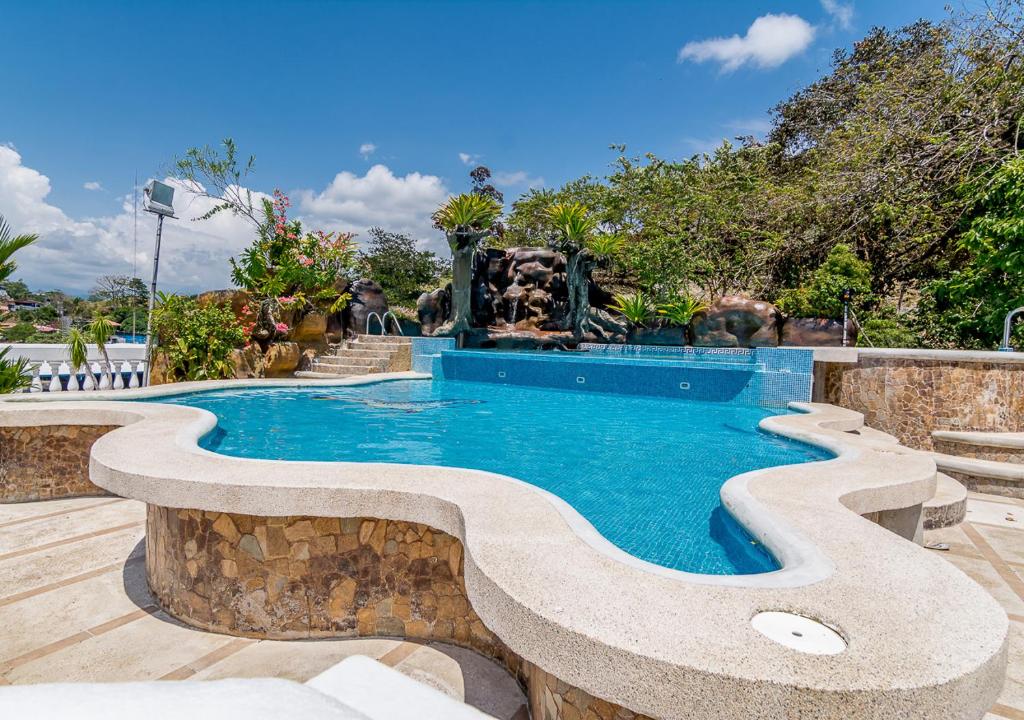 a swimming pool with a fountain in a resort at Hotel Le Priss in Manuel Antonio