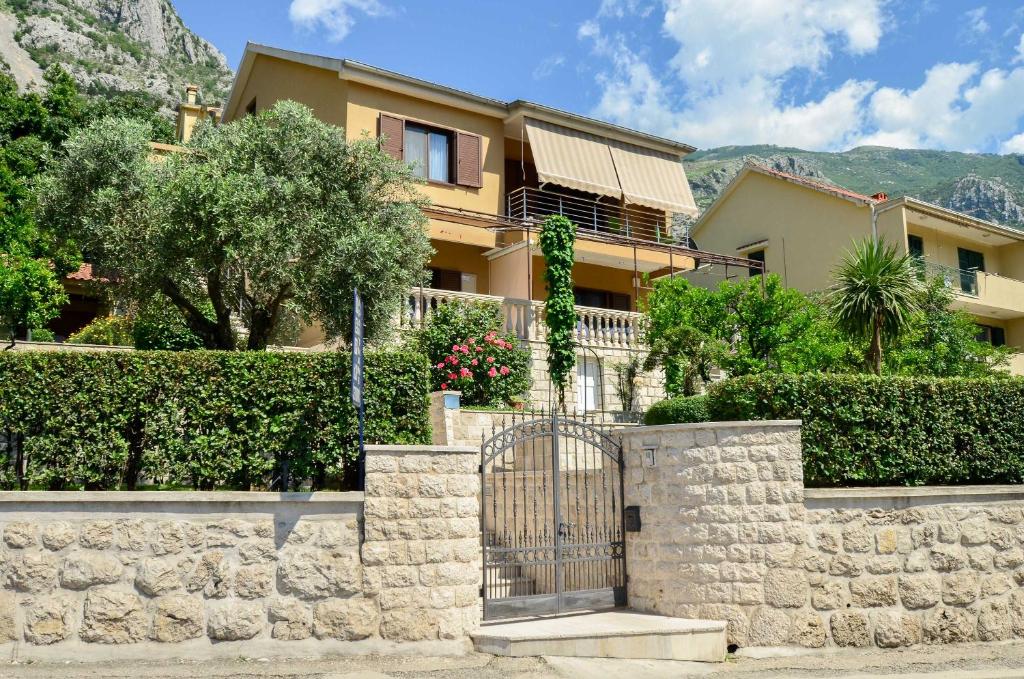 a house with a stone fence and a gate at Apartmani Ćetković in Kotor
