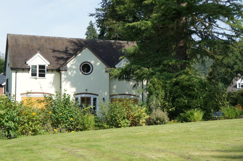 a white house with a large lawn in front of it at Berries Coach House in Church Stretton