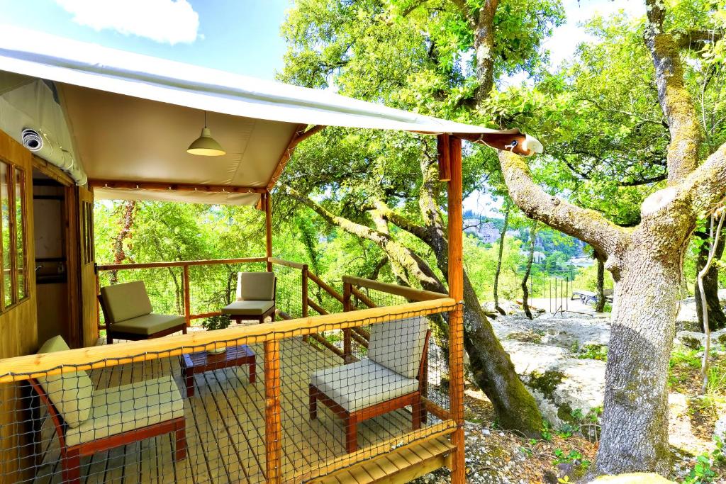 a porch with two chairs and a tree at Cabanes Lodges Le Servière in Balazuc
