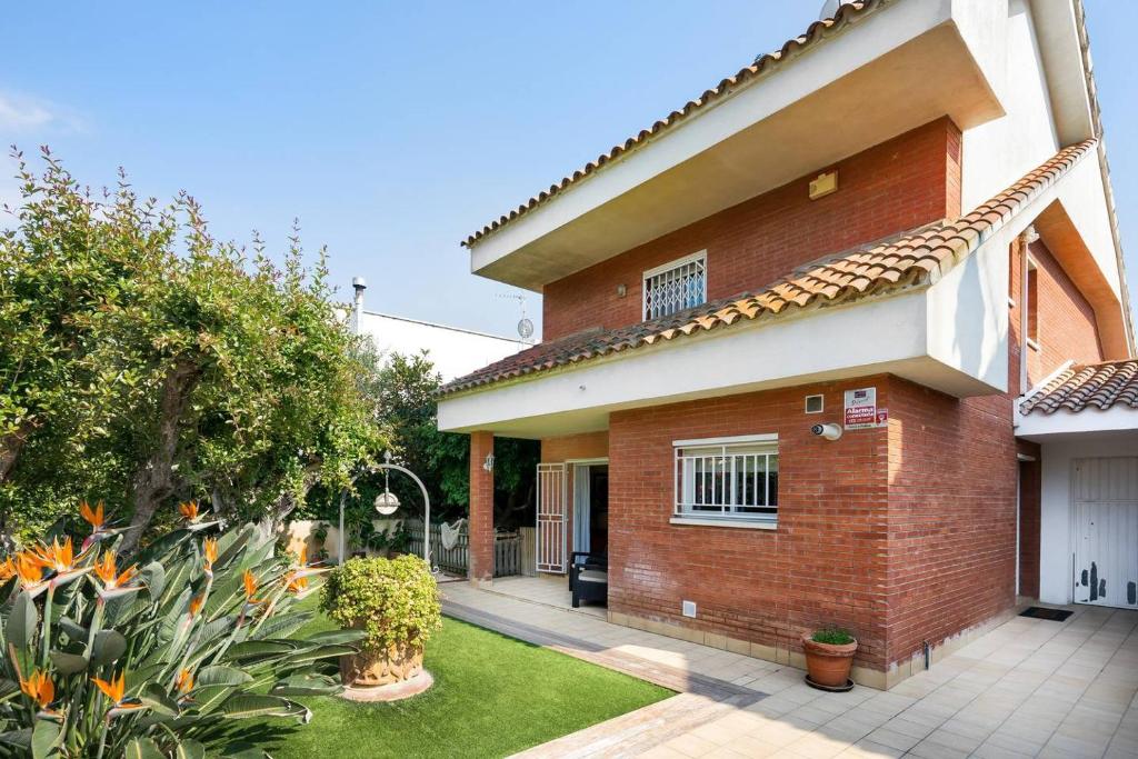 una casa de ladrillo rojo con un patio delante en Preciosa casa cerca de la playa, en Castelldefels