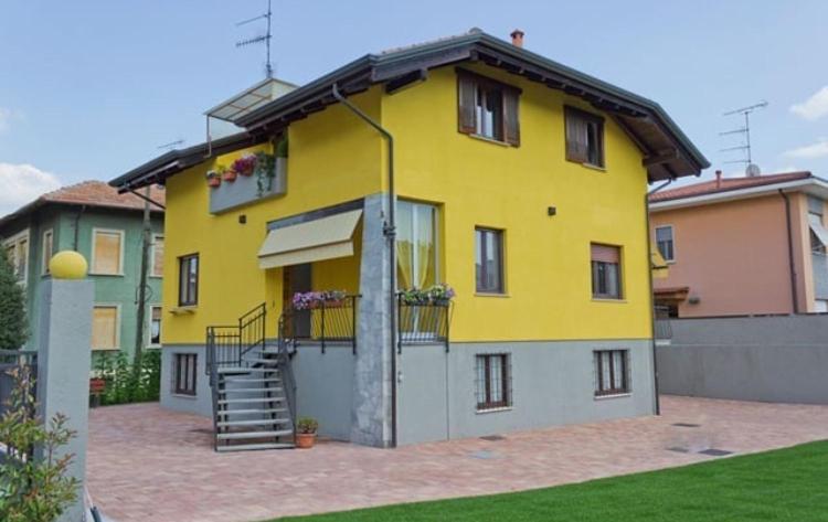 a yellow house with a staircase in a yard at Il Gatto Stanco B&B in Arona