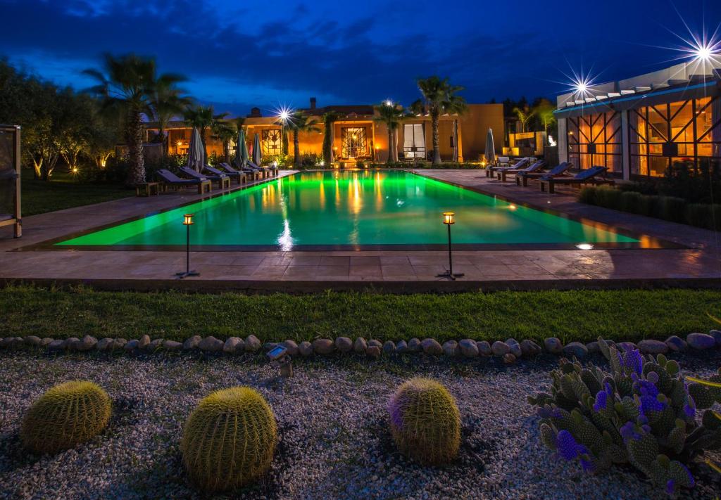 - une piscine de nuit avec des chaises et des cactus dans l'établissement Villa Imperiale, à Marrakech
