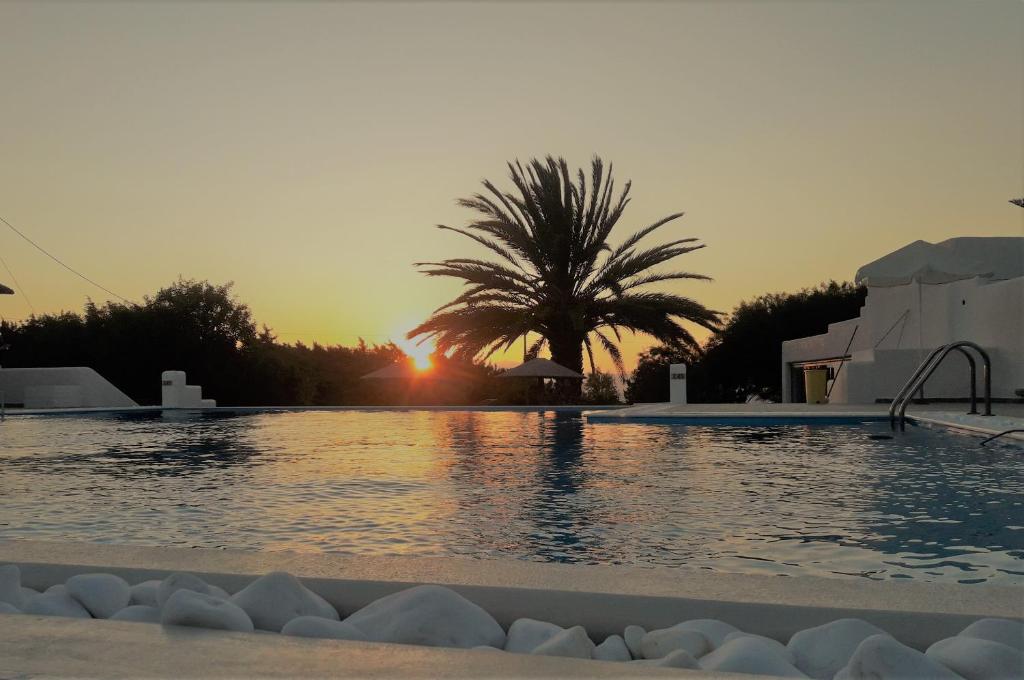 a swimming pool with a sunset in the background at Villa Faros in Aliko Beach
